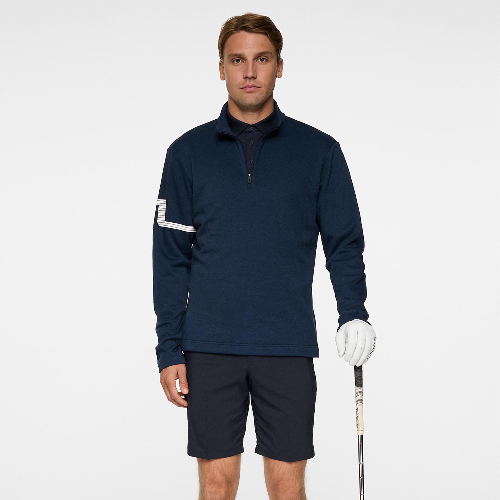 Model wearing J.Lindeberg Heath Strike Golf Mid Layer holding golf club