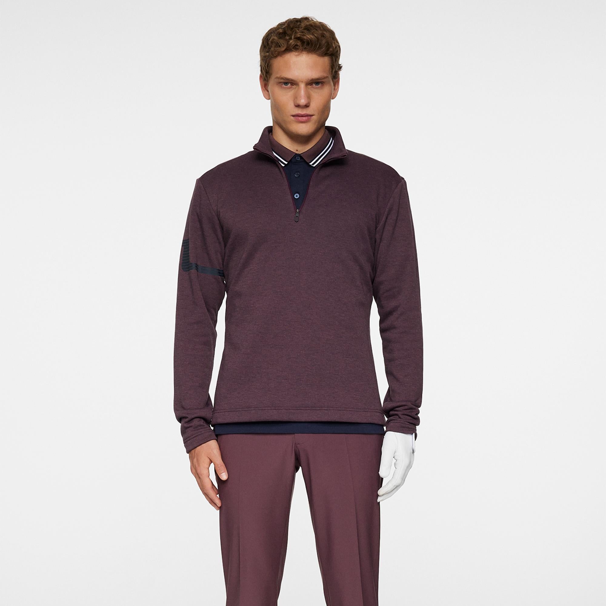 Model holding club wearing J.Lindeberg Heath Strike Mid Layer in Huckleberry
