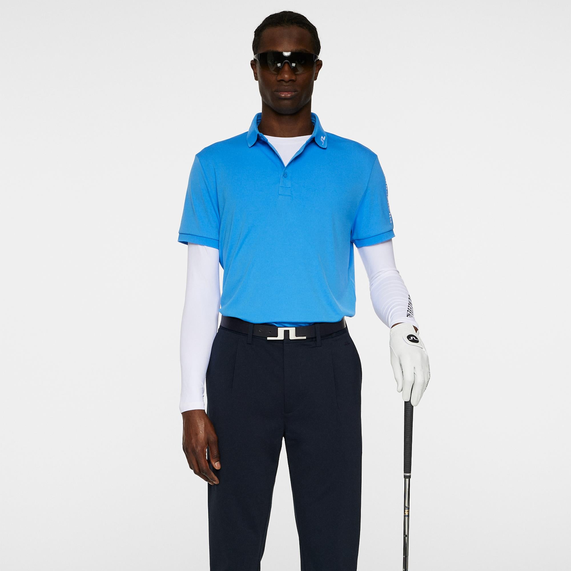 Model holding golf club wearing J.Lindeberg Tour Tech Men’s Polo – Sonic Blue