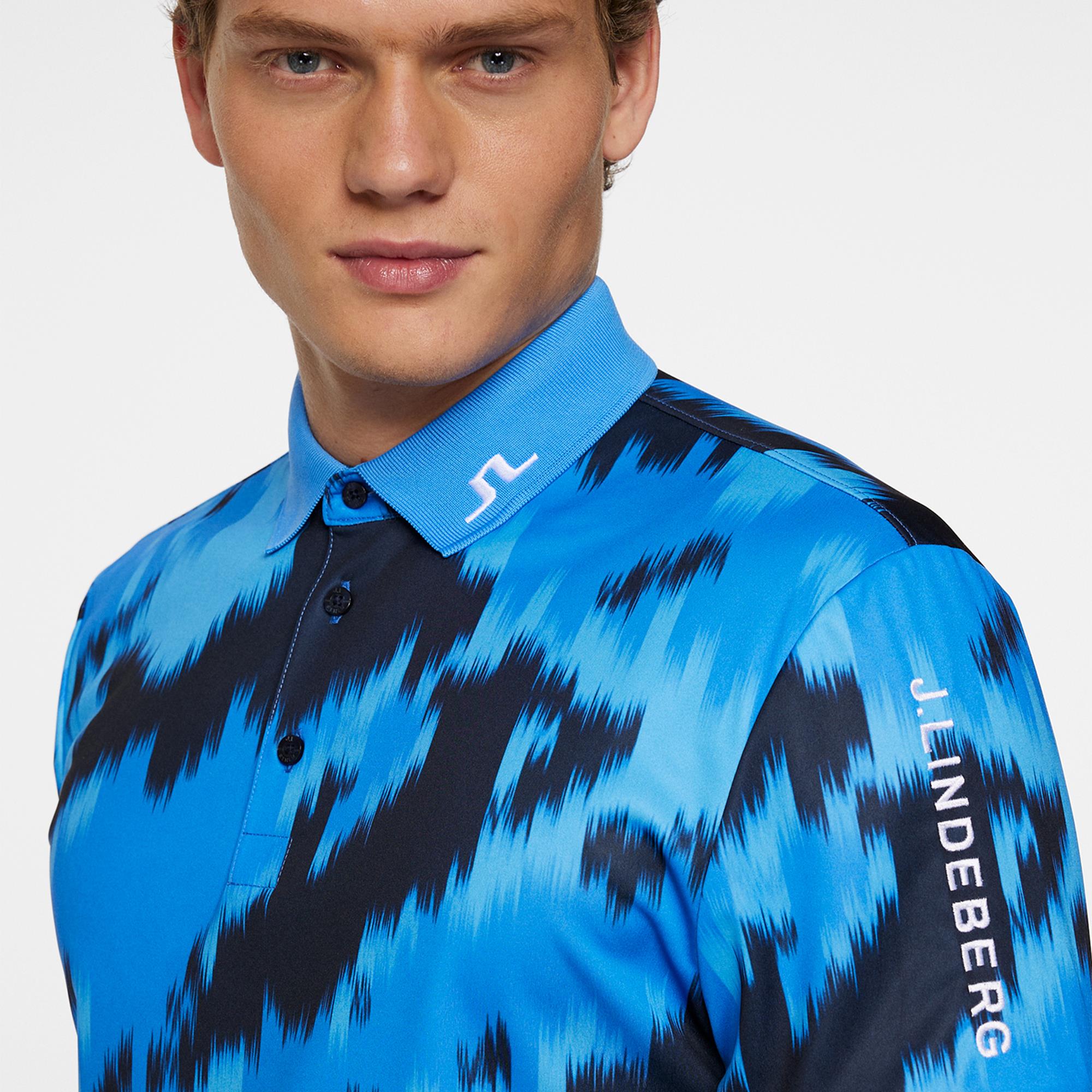 Man wearing a blue and black patterned shirt with 'J.Lindeberg' branding on a light gray background